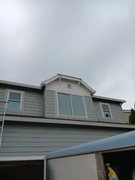 New windows set in a dormer and upper wall on a gray two-story