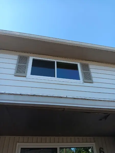 White slider window with shutters above a porch